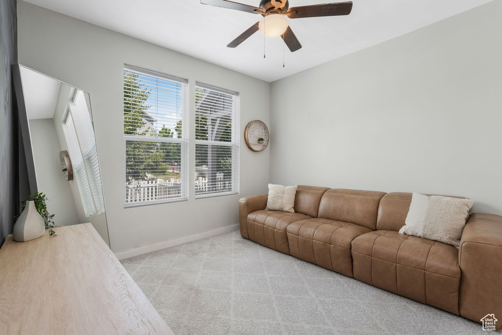 Carpeted living area featuring baseboards and a ceiling fan