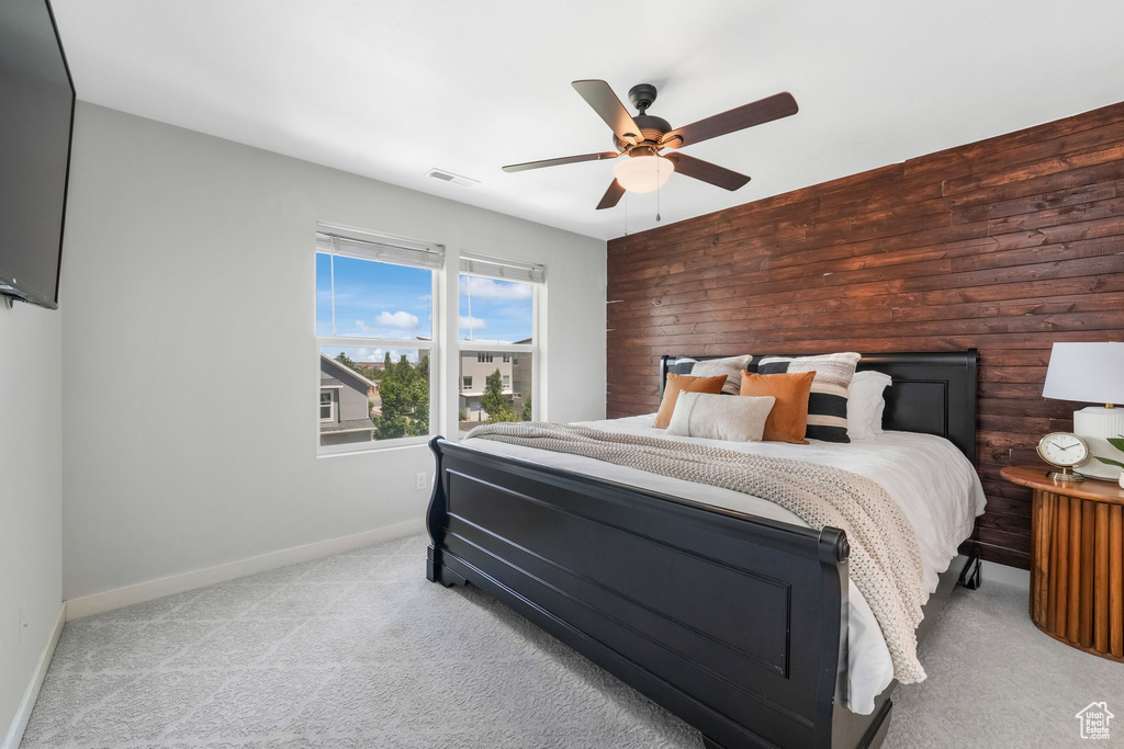 Bedroom featuring carpet flooring, wooden walls, and ceiling fan