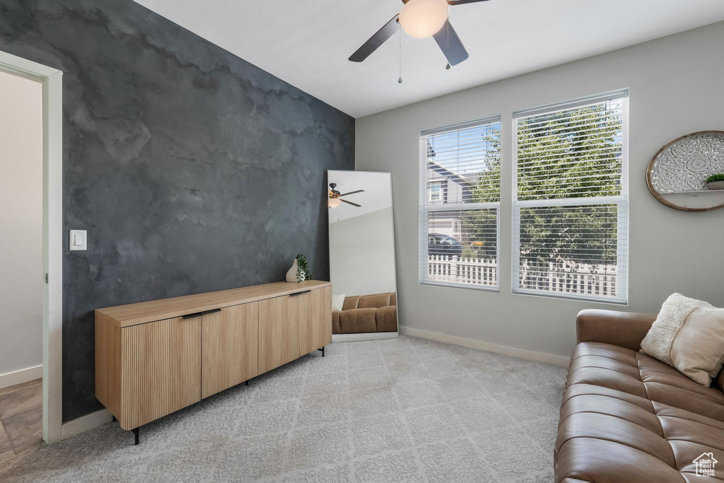 Living area with a ceiling fan and light carpet