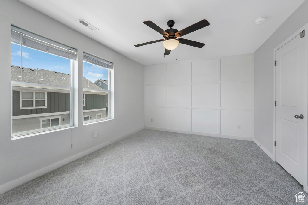 Carpeted empty room featuring a ceiling fan and a smoke detector