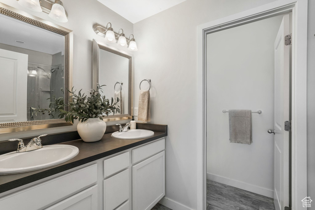 Full bath featuring double vanity, wood finished floors, and a shower