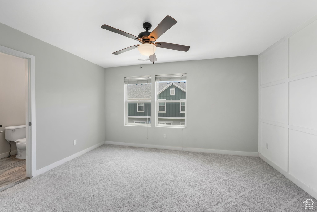 Unfurnished bedroom with light carpet, ensuite bath, and a ceiling fan
