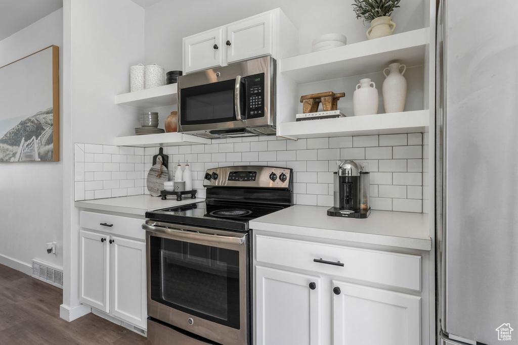 Kitchen featuring appliances with stainless steel finishes, open shelves, backsplash, and light countertops