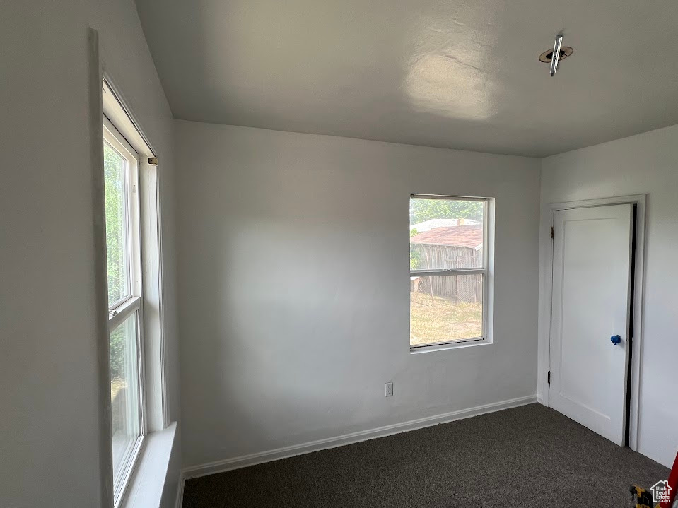 Spare room with dark colored carpet and baseboards