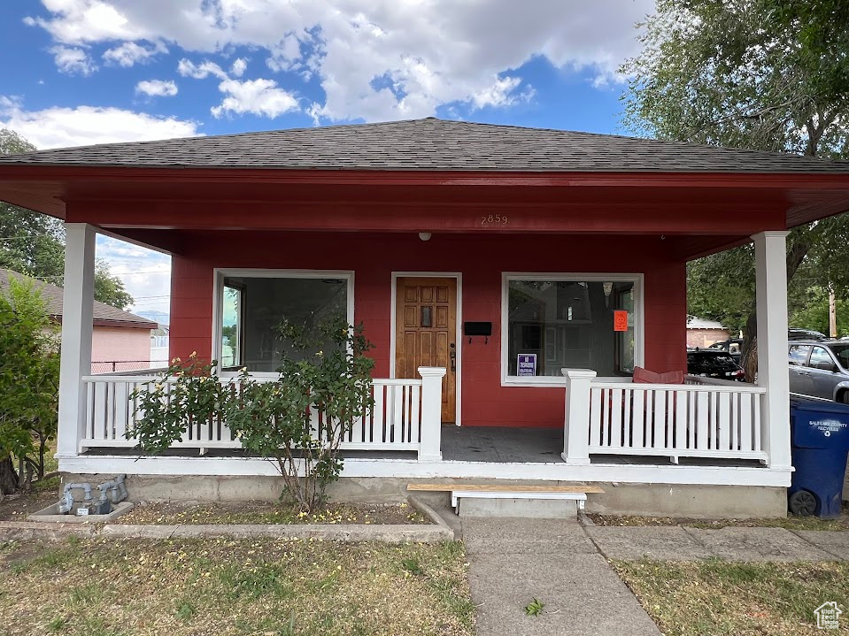 View of front facade with a porch and roof with shingles