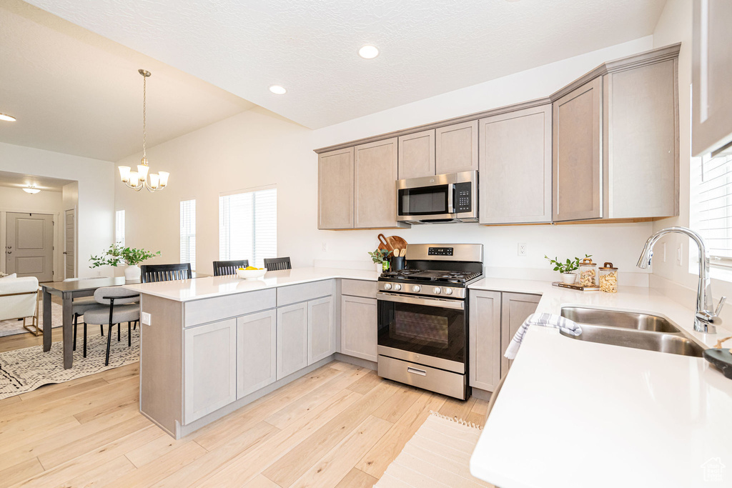 Kitchen featuring stainless steel appliances, a peninsula, a chandelier, recessed lighting, and light countertops