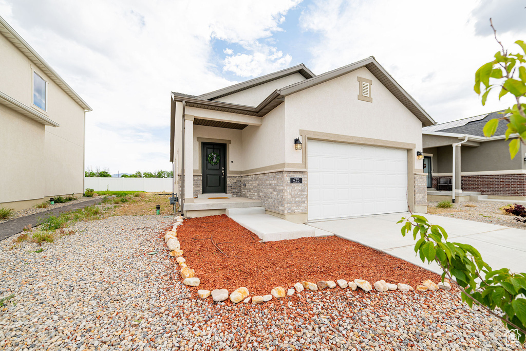 View of front facade featuring an attached garage, concrete driveway, and stucco siding
