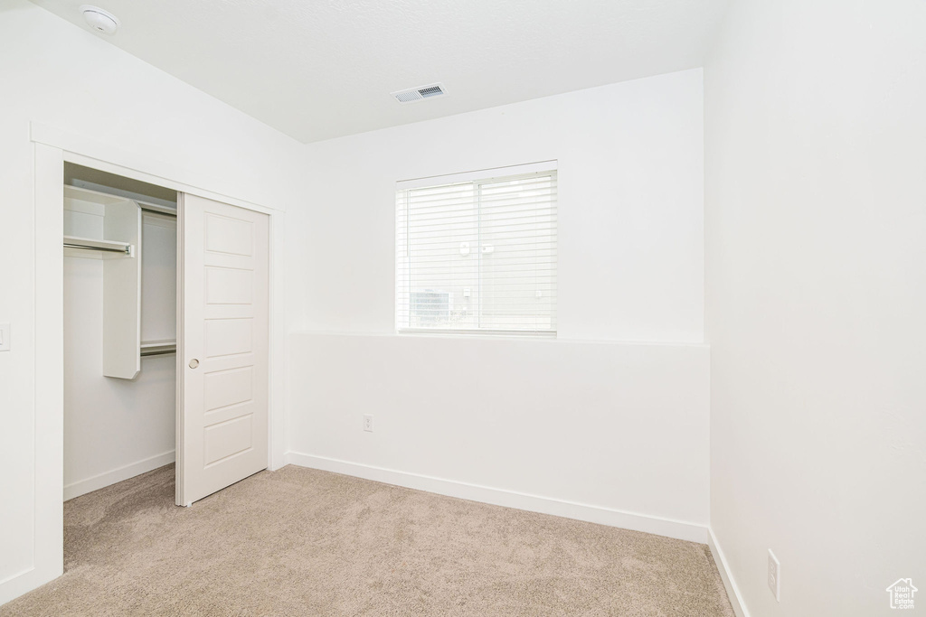 Unfurnished bedroom featuring light colored carpet and a closet