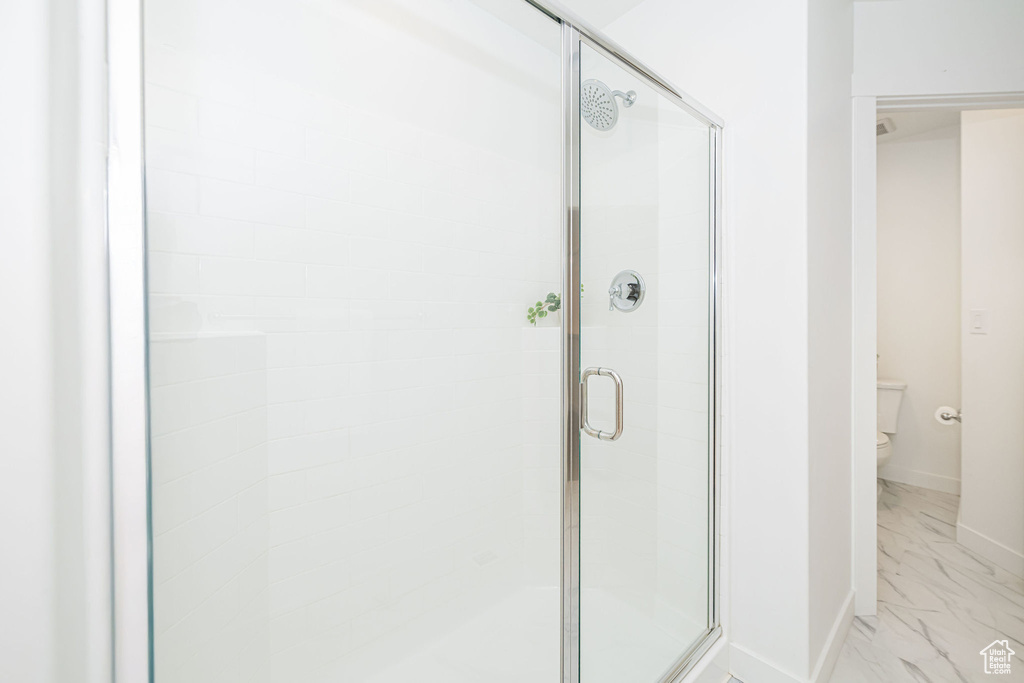 Full bathroom with marble look tile flooring and a stall shower