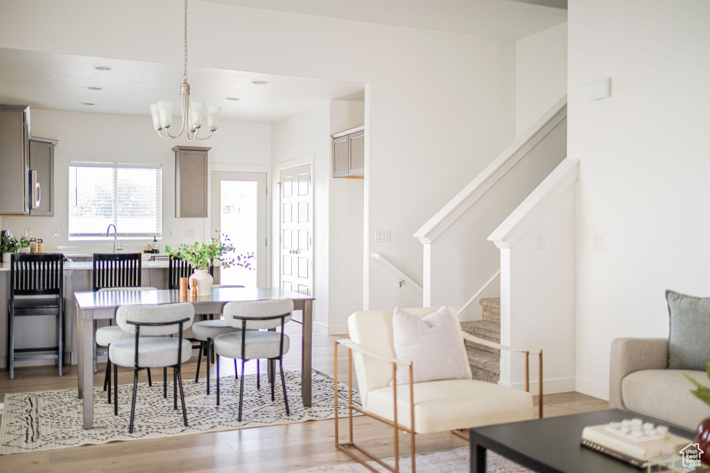 Dining area featuring stairs, light wood finished floors, and a chandelier