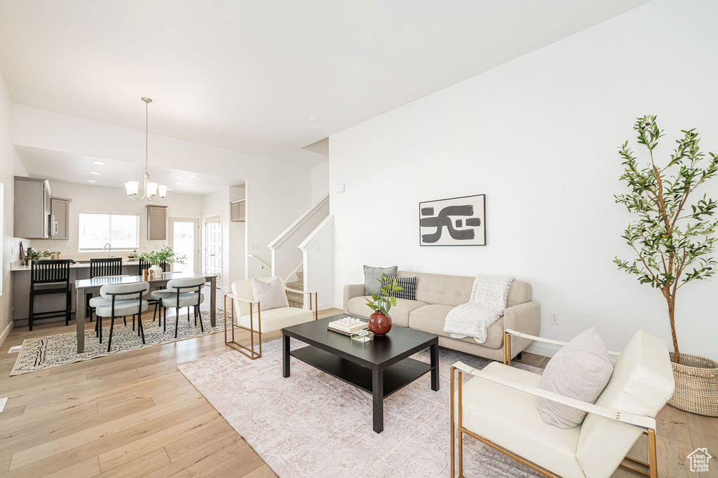 Living room featuring light wood finished floors, stairway, a chandelier, and recessed lighting