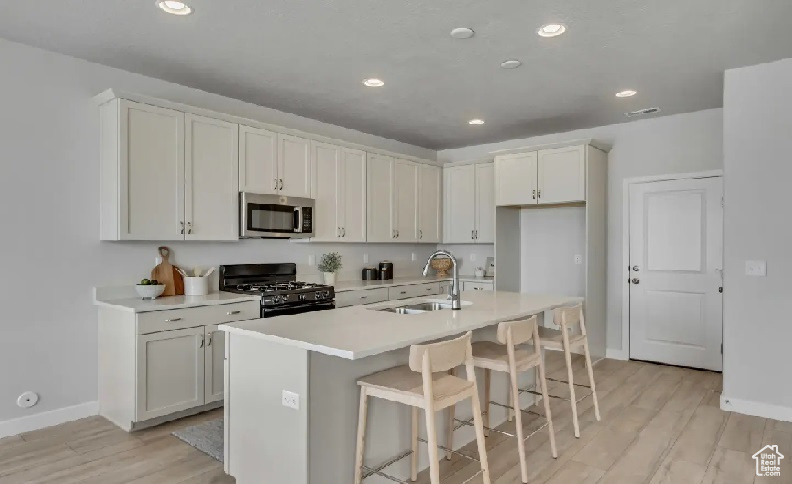 Kitchen featuring gas stove, stainless steel microwave, light wood-style floors, light countertops, and recessed lighting