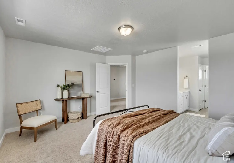 Bedroom with light carpet and ensuite bath