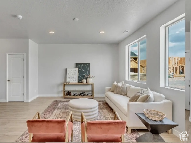 Living room with light wood-type flooring, stairway, and recessed lighting
