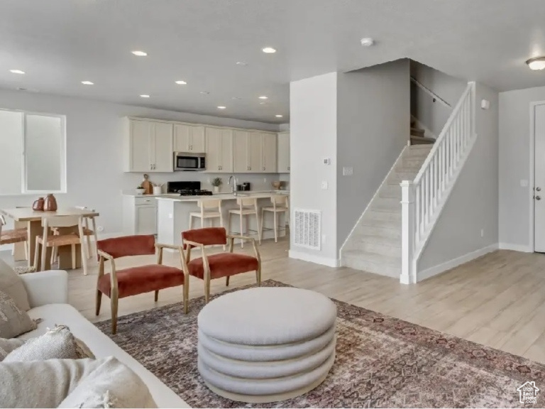 Living area with stairs, light wood-type flooring, and recessed lighting