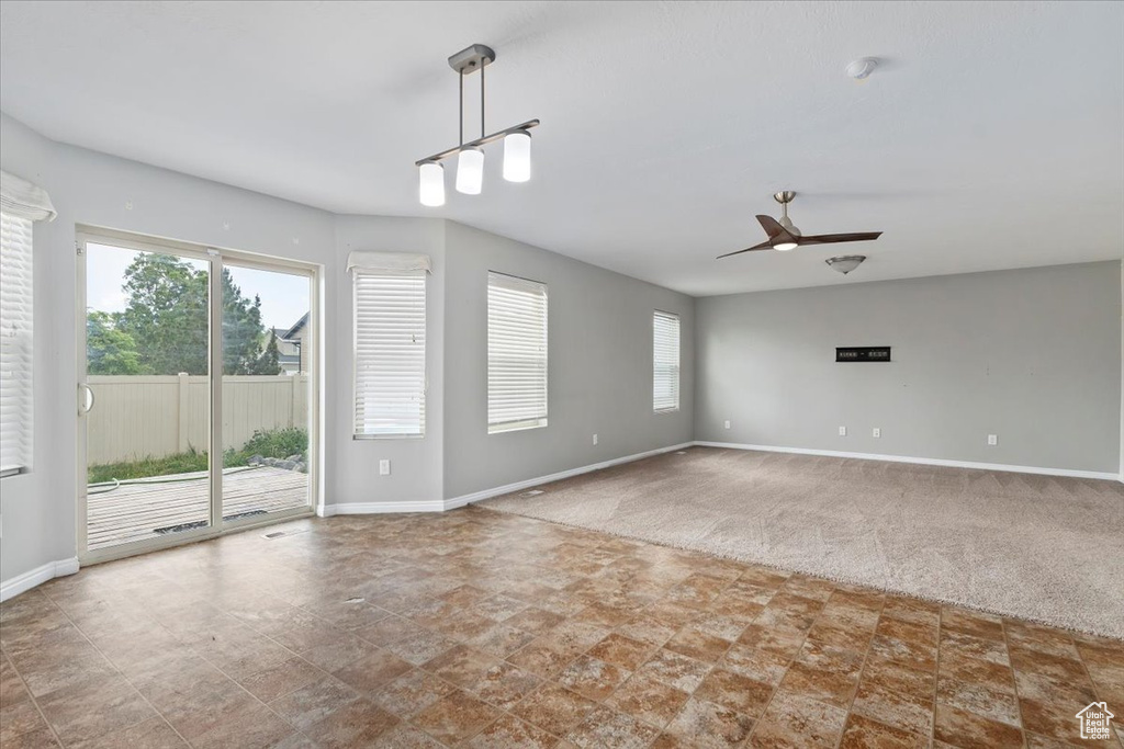 Empty room featuring stone finish floors, a ceiling fan, and carpet