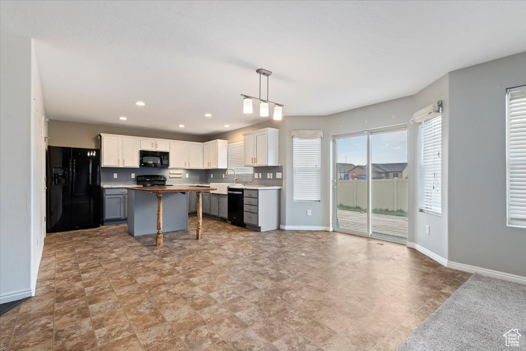 Kitchen featuring black appliances, white cabinets, a center island, recessed lighting, and open floor plan
