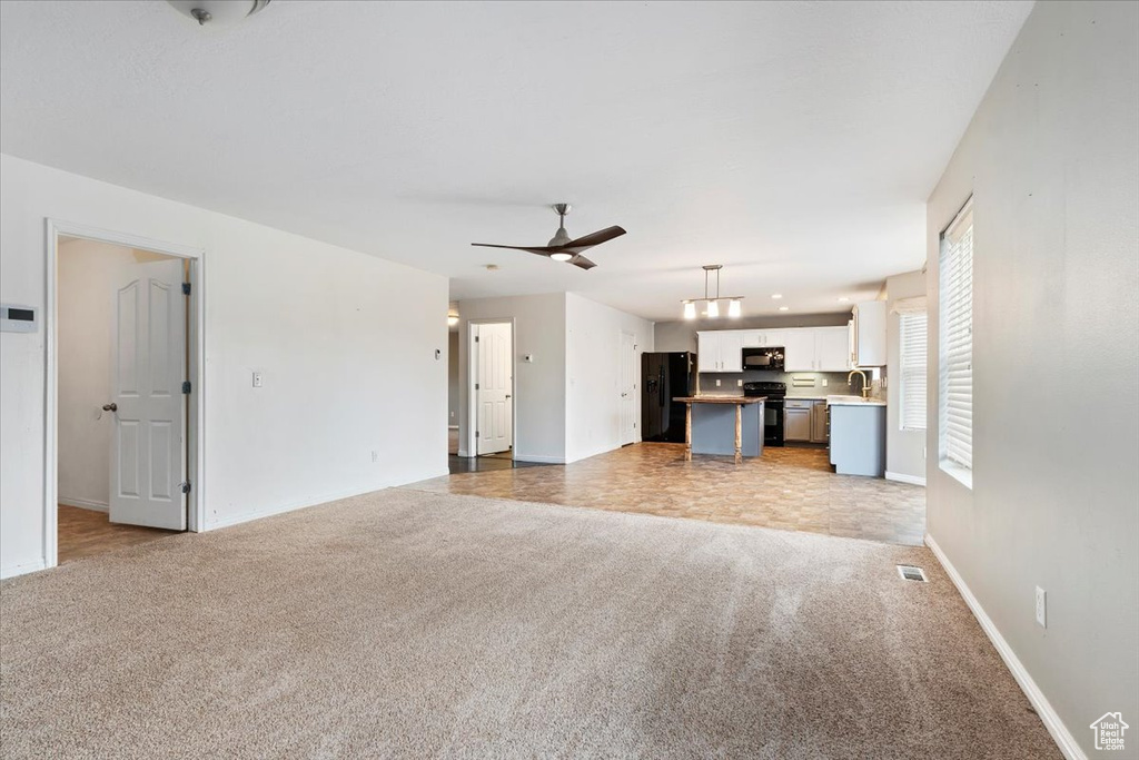 Unfurnished living room with light colored carpet and ceiling fan