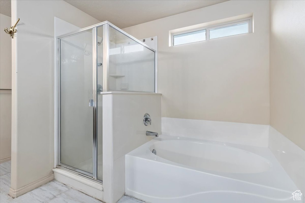 Full bath featuring a stall shower, a garden tub, and marble finish floors