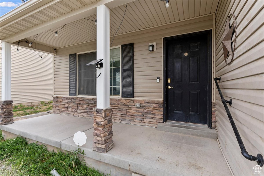 Doorway to property with covered porch and stone siding