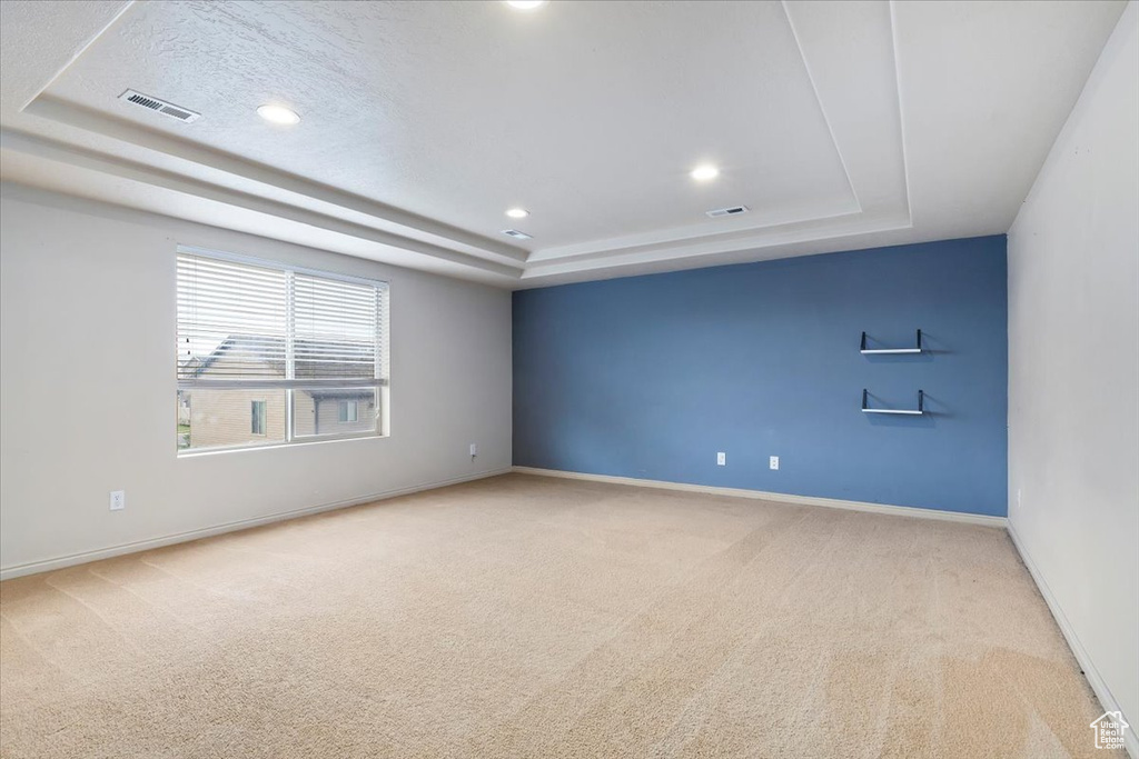 Carpeted spare room featuring a raised ceiling and recessed lighting