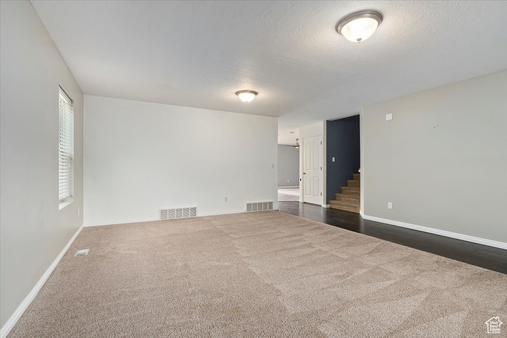 Empty room with dark carpet and stairway