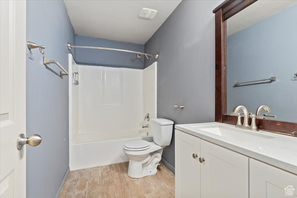 Bathroom with wood finished floors, vanity, and bathing tub / shower combination