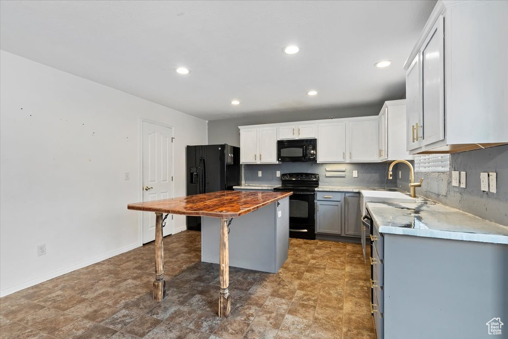 Kitchen featuring black appliances, recessed lighting, gray cabinets, a kitchen breakfast bar, and tasteful backsplash