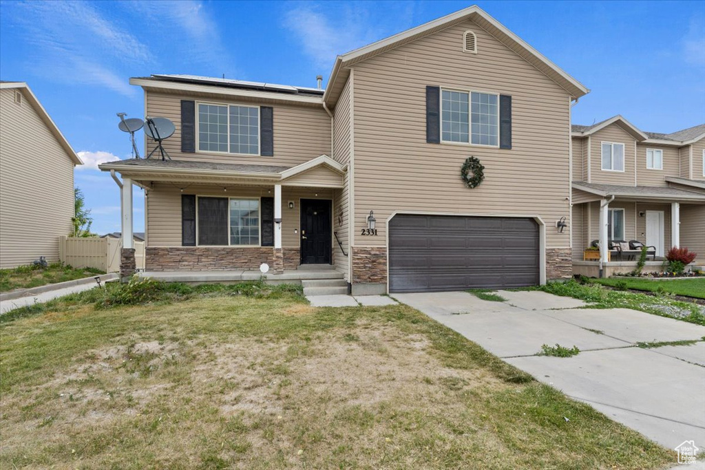 View of front of house featuring a porch, an attached garage, driveway, and stone siding