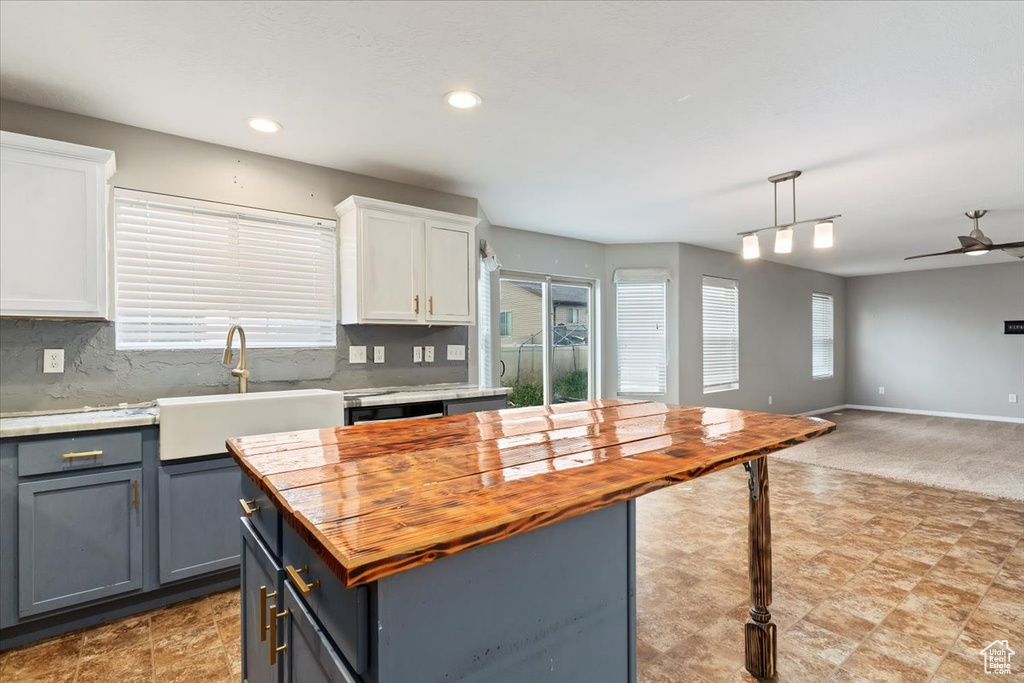 Kitchen featuring wooden counters, open floor plan, white cabinets, a kitchen island, and recessed lighting