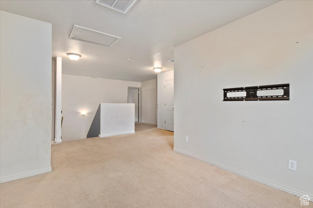 Carpeted empty room featuring attic access and baseboards