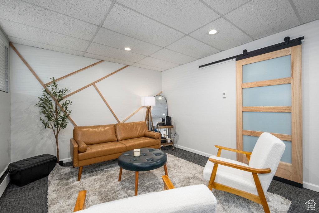 Carpeted living room featuring a barn door, recessed lighting, and a paneled ceiling