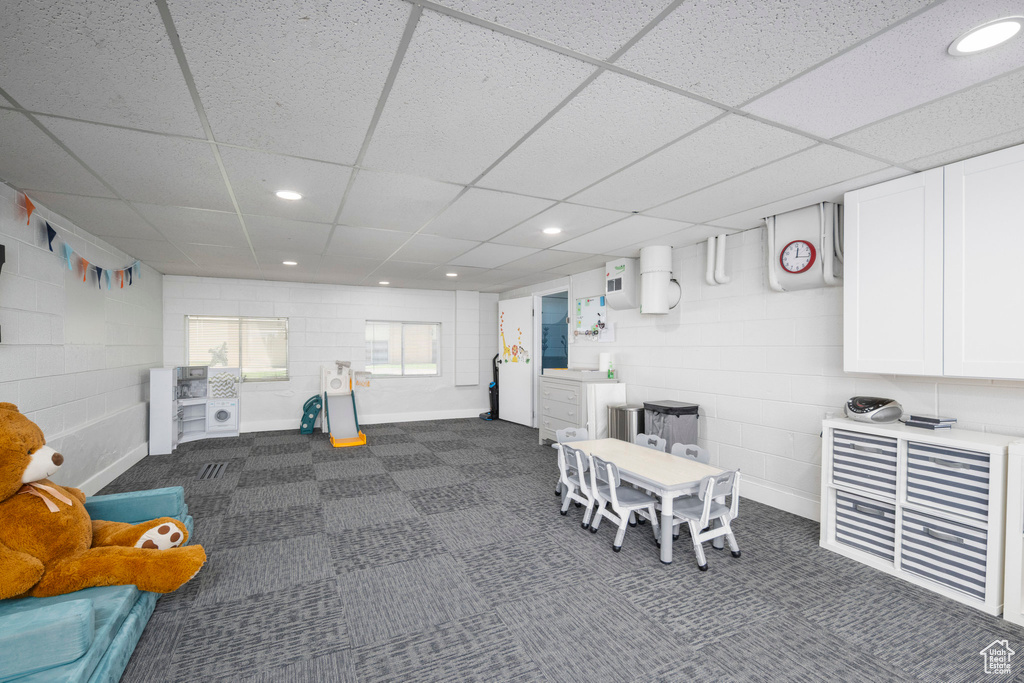 Game room featuring a paneled ceiling, concrete block wall, recessed lighting, and dark carpet