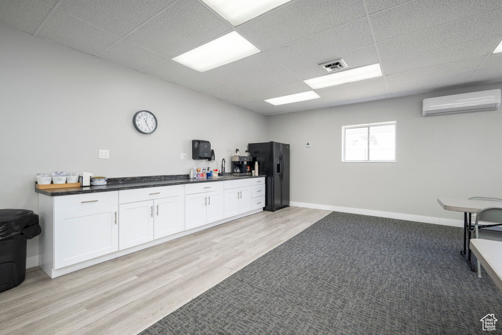 Misc room with a wall mounted air conditioner, a drop ceiling, and light wood-type flooring