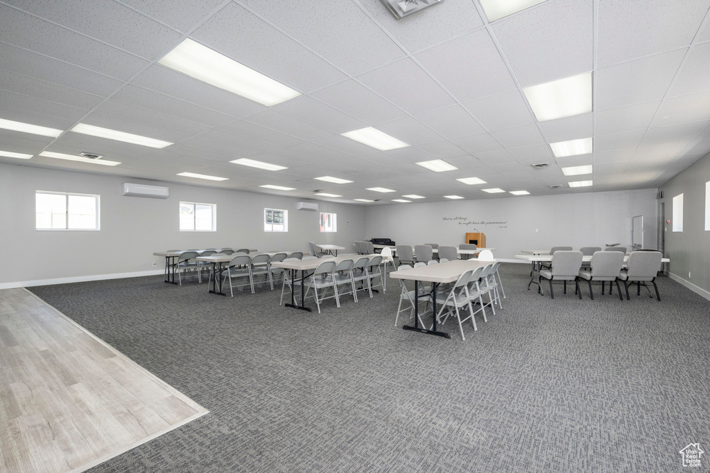 Carpeted dining area with a wall mounted AC and a drop ceiling