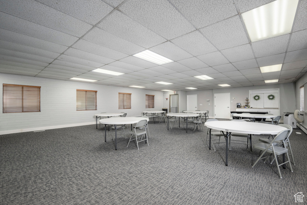 Carpeted dining room featuring a drop ceiling and baseboards
