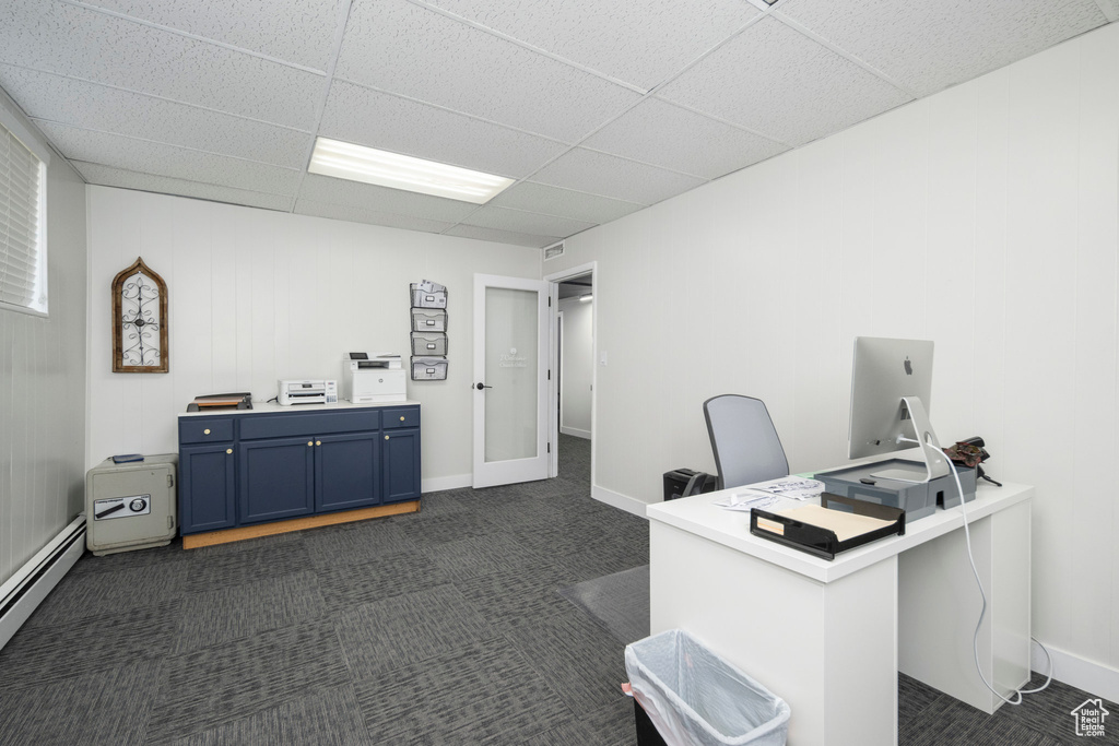 Home office featuring a baseboard heating unit, dark colored carpet, and a drop ceiling