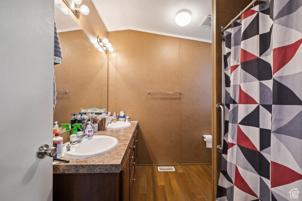 Bathroom featuring wood finished floors, double vanity, and crown molding