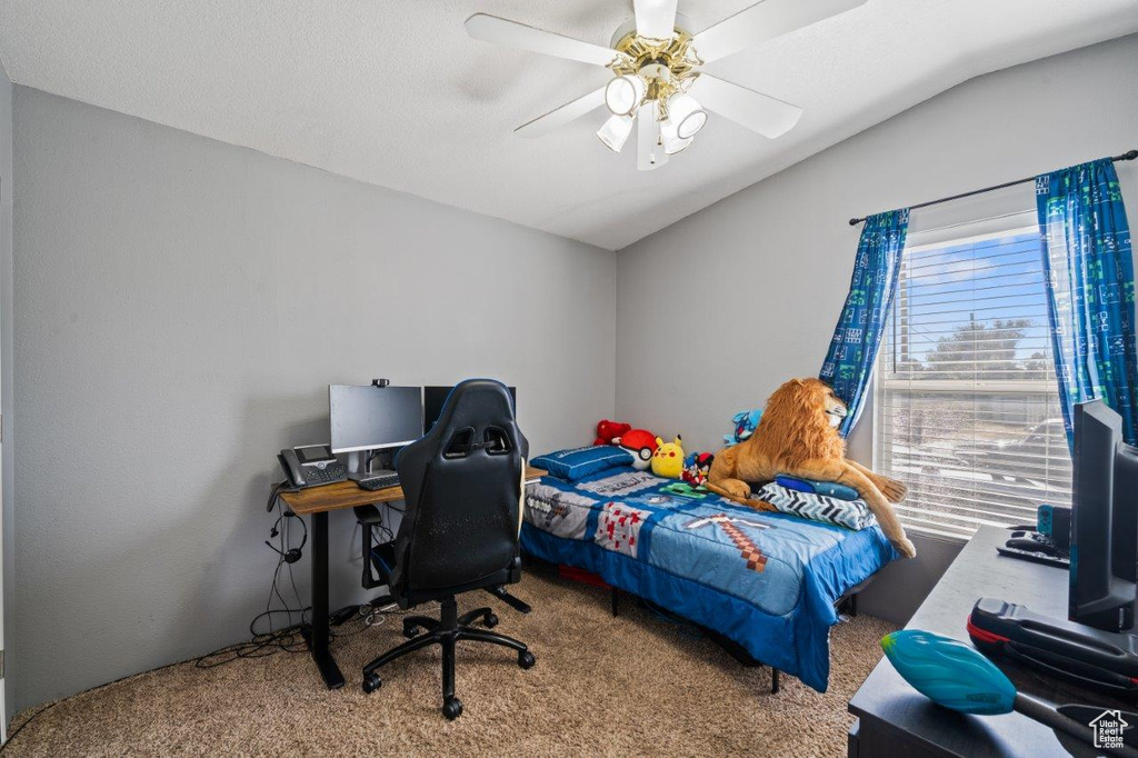 Carpeted bedroom with vaulted ceiling, a ceiling fan, and an office area