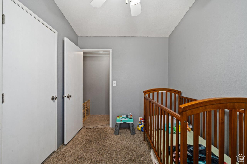 Bedroom featuring carpet floors, a crib, and ceiling fan