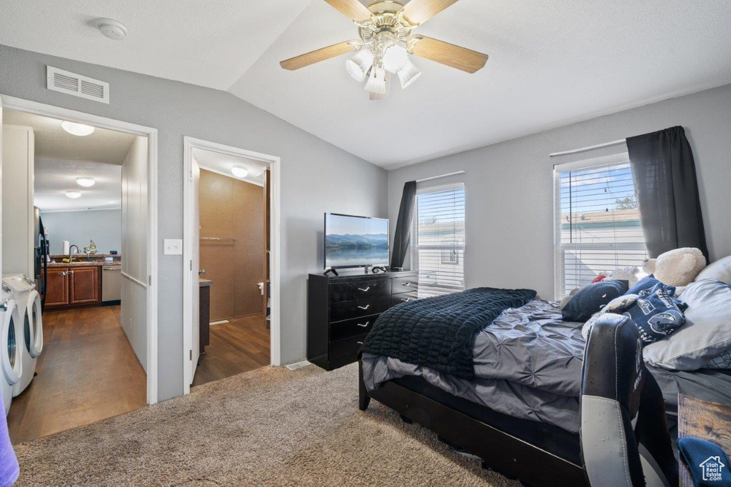 Bedroom featuring washing machine and dryer, lofted ceiling, carpet, ceiling fan, and ensuite bathroom