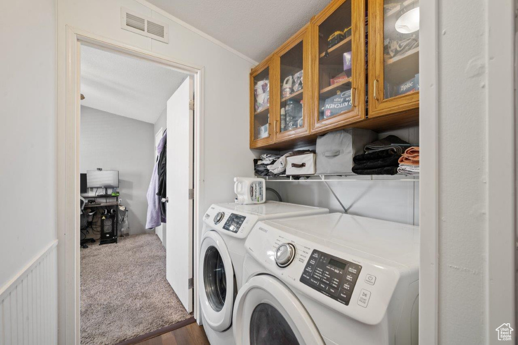 Laundry room with washing machine and dryer, crown molding, and wood finished floors