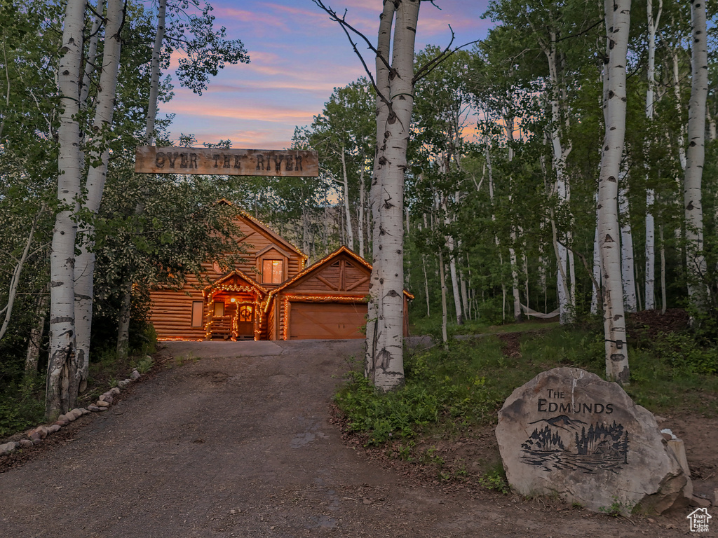 View of front of property featuring dirt driveway and a garage