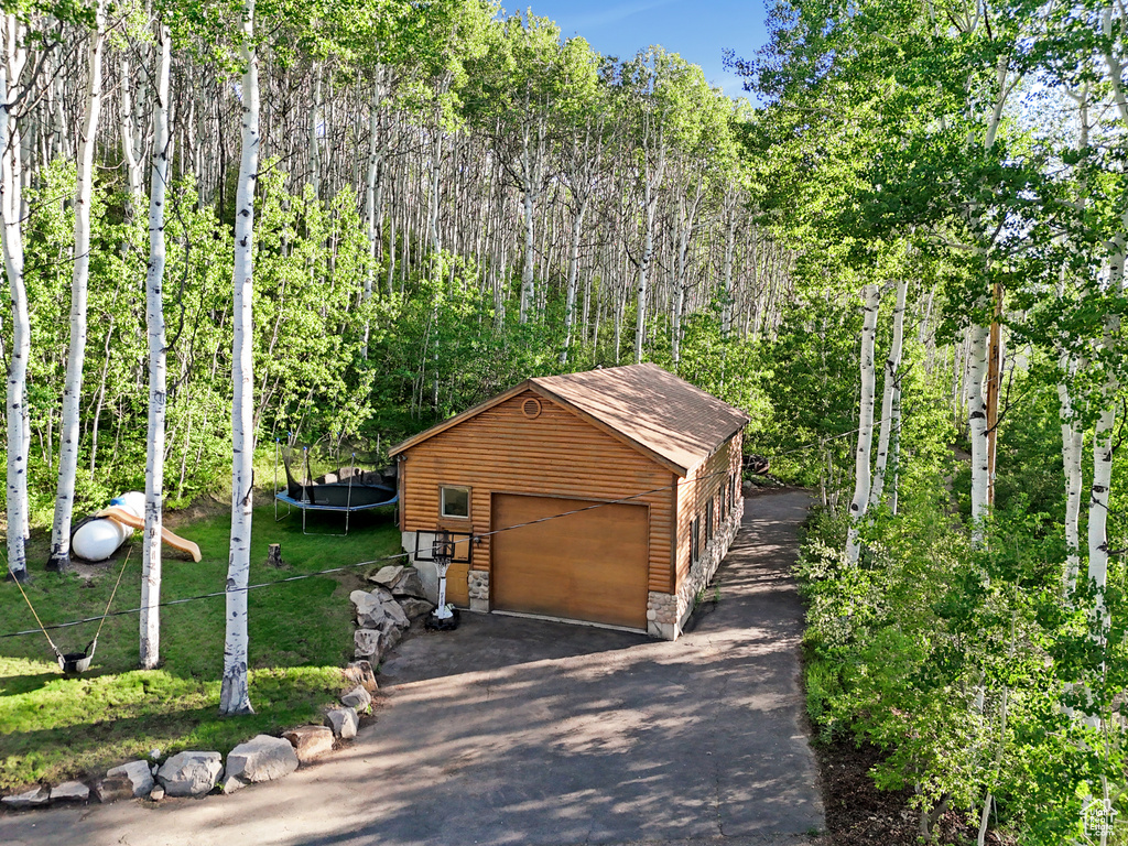 Detached garage featuring a trampoline and asphalt driveway