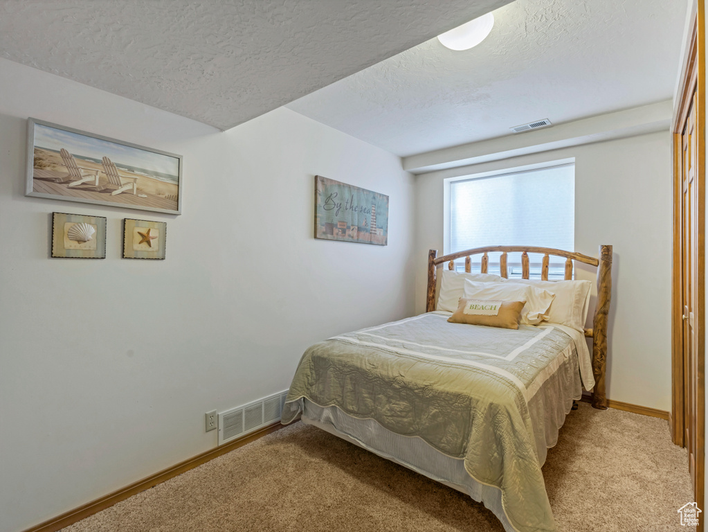 Carpeted bedroom with a textured ceiling and baseboards