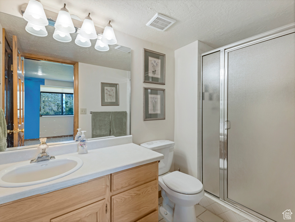 Full bath with vanity, a stall shower, tile patterned flooring, and a textured ceiling
