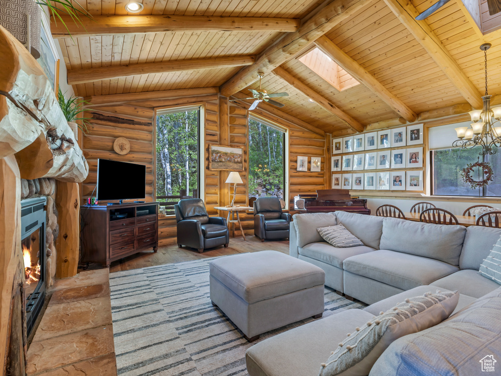 Living area featuring wooden ceiling, rustic walls, a skylight, a chandelier, and a stone fireplace