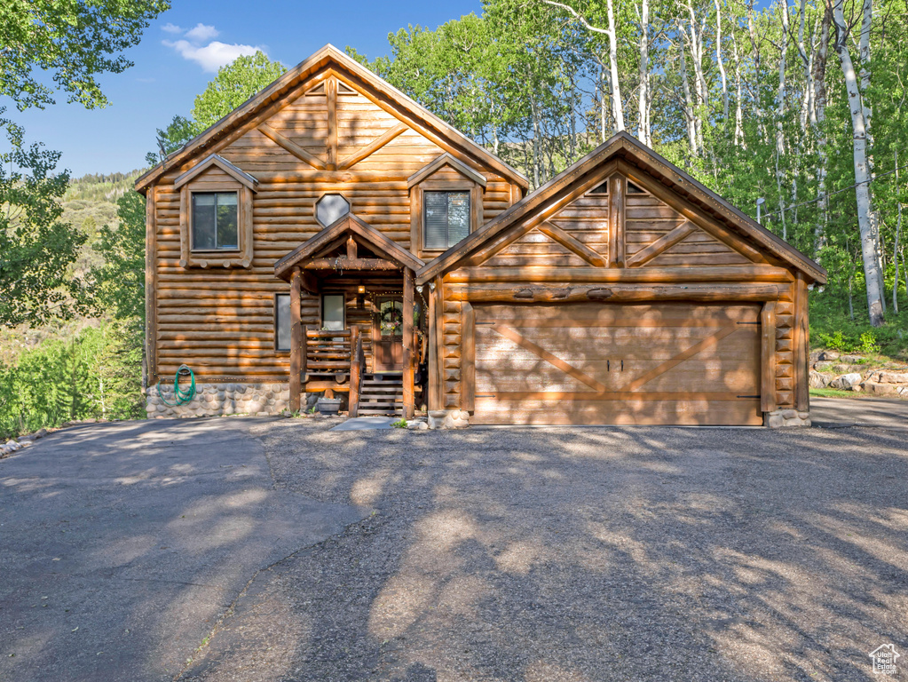View of front of property featuring asphalt driveway and an attached garage
