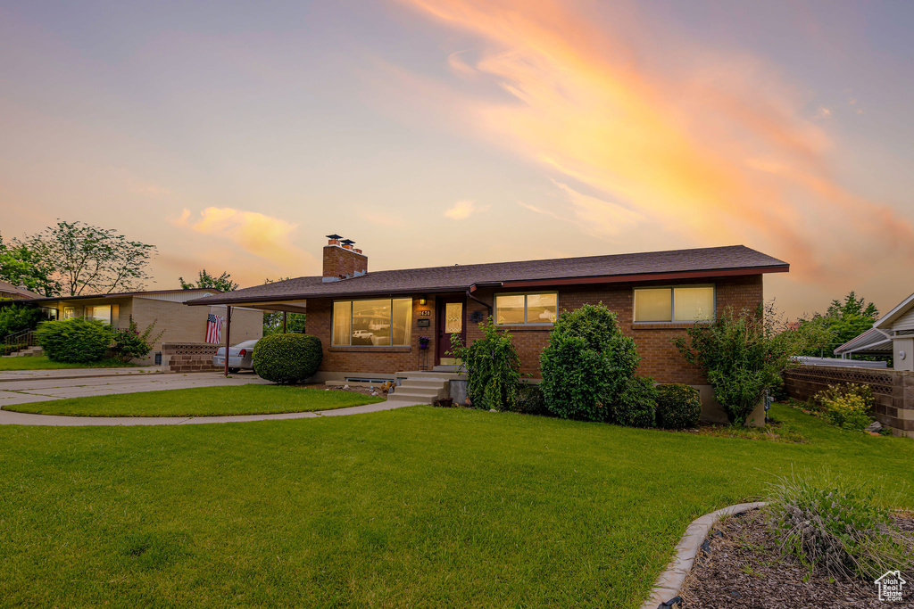 Ranch-style home with brick siding, a chimney, a front yard, and concrete driveway