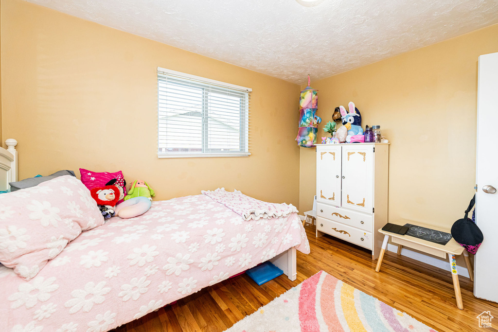 Bedroom with wood finished floors and a textured ceiling